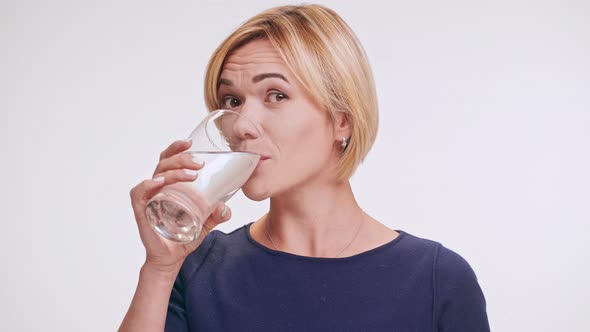 Beautiful Middleaged Caucasian Blonde Female in Blue Sweatshirt Drinking Water From Glass Smiling