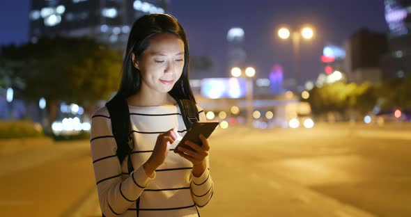 Woman use of mobile phone in city at night 