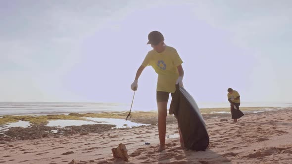 Volunteer Wearing a Green Tshirt Tidying Up Rubbish with a Trash Grabber Stick