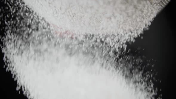 Flour Is Sifted Through a Sieve on Black Background