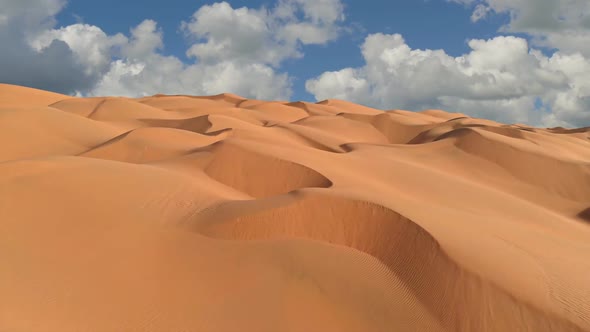 Flying Over Endless Yellow Sand Dunes in Desert. Sand Dunes and Blue Sky with Clouds. Aerial View of