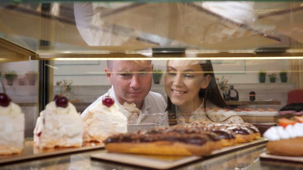 Happy Couple Chooses Tasty Cakes in Glass Show Case of Shop
