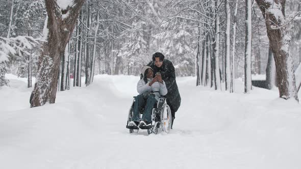 Young Couple of Asian Guy and His Black Girlfriend in the Wheelchair Taking a Selfie in Winter