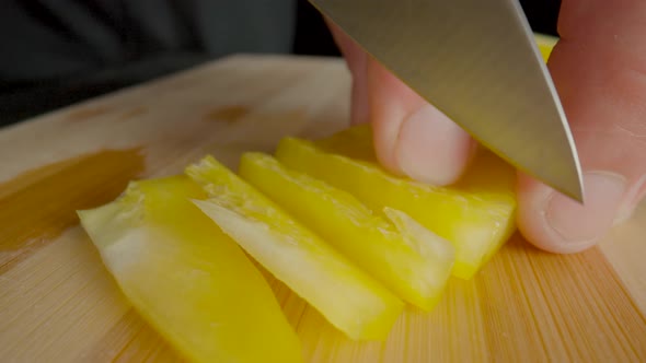 Hands of Man with Knife Slicing Yellow Sweet Pepper Into Long Pieces