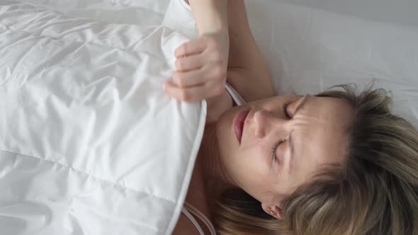 Frightened Woman Waking Up Looks Under Covers on Bed