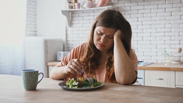 Plus Size Woman Sitting at Table Feeling Unhappy with Diet Not Wanting to Eat Salad