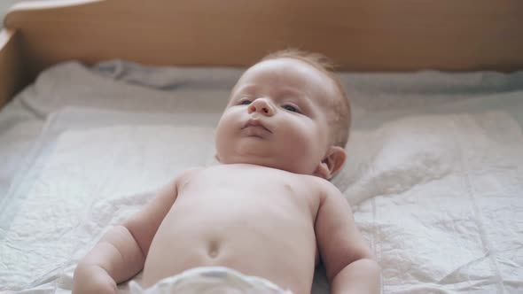 Serious Newborn Son with Short Fair Hair and in White Diaper