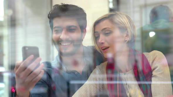 Video call. Happy couple using phone in cafe indoors