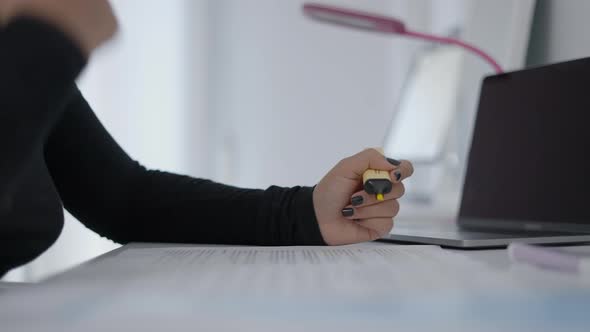 A Young Student Sitting at a Table and Reading Her Study Material and Holding a Highlighter in Her