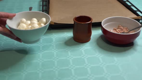 Woman leaving bowl with mozzarella balls on turquoise table, ingredients for pizza