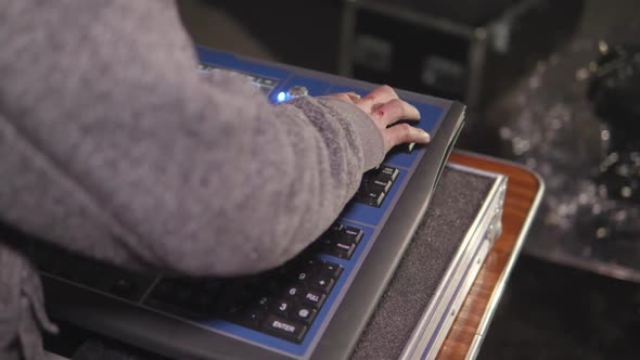 Young media console operator presses buttons on the console to set up and prepare for an outdoor eve