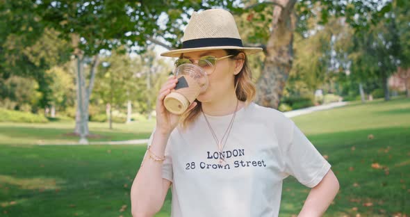 Pretty Woman Is Enjoying Iced Coffee Drink in the Green Park During Lunch Time