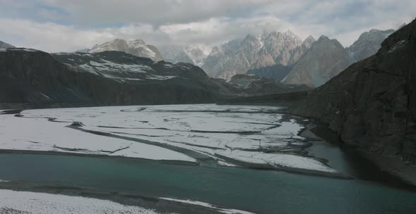 Aerial Dolly Over Hunza River With Tilt Up View Across Epic Snow Capped Mountain Range In Distance.