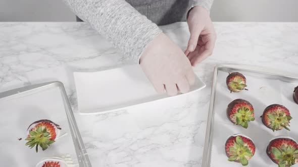 Step by step. Arranging chocolate strawberries on a white serving plate.