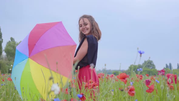 Cute Young Girl Spinning Colorful Umbrella Dancing in a Poppy Field Smiling Happily Looking in the