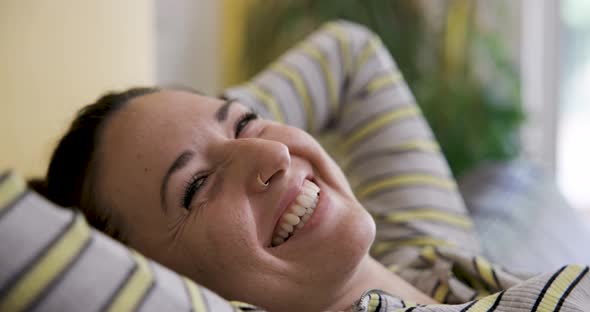 Happy woman on the sofa relaxing and smiling, enjoying a nice day