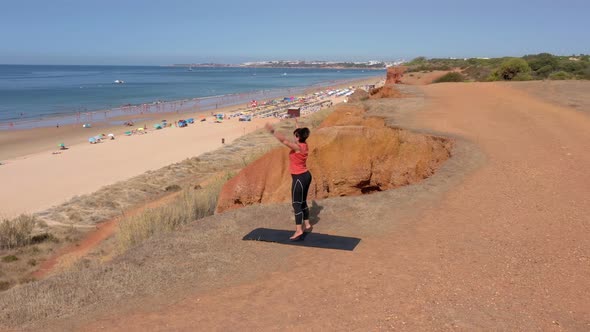 A Middleaged Woman on the Ocean Shore Goes in for Sports Gymnastics