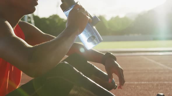 Disabled mixed race man with prosthetic legs sitting on racing track