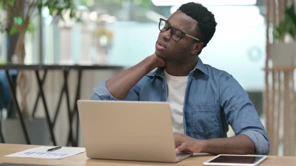 Young African Man Having Neck Pain While Typing on Laptop