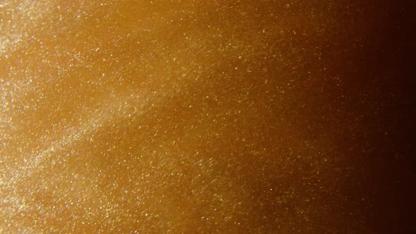 Macro shot of gold glitter. Slow mo. Amazing background. 4K. Gold liquid. Boke.