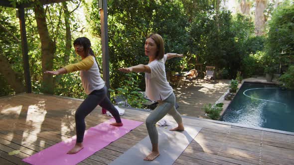 Asian mother and daughter practicing yoga outdoors in garden