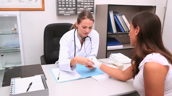 Doctor sitting at her office touching patient wrist