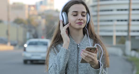 Woman Listening To Music with Headphones in City