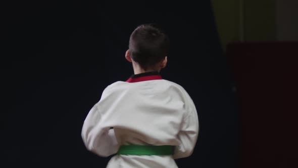 A Little Boy Doing Martial Arts  Jumping on the Spot and Showing a Kick From the Turn