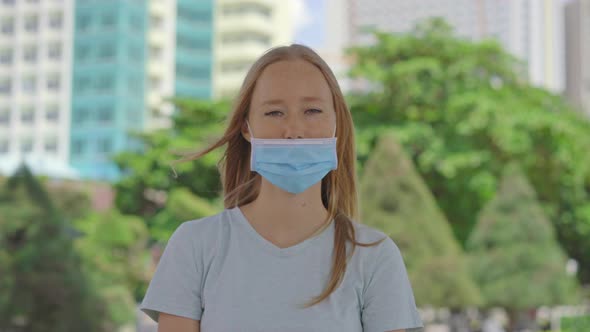 A Young Woman Stands on a Street. She Is Wearing Medical Face Mask in the Wrong Way