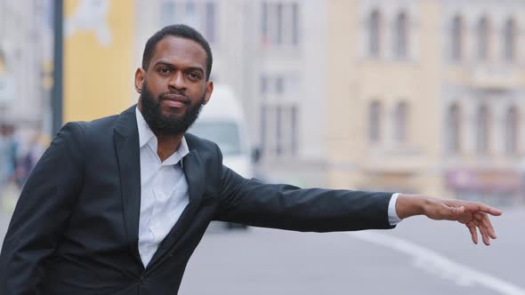 Young Black Bearded Businessman Standing on Sidewalk Outdoors Waving Hand Signaling to Driver Stop