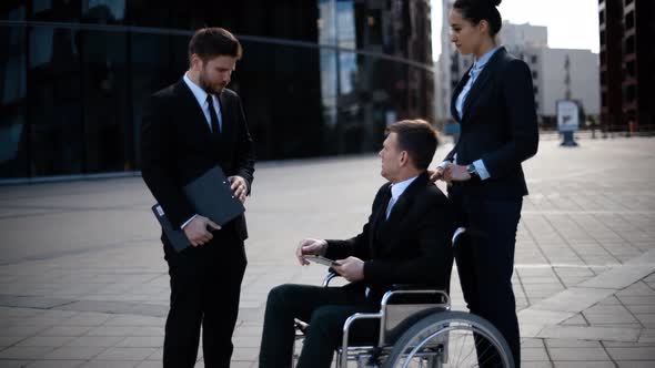 Young Disabled Entrepreneur Businessman Talk with His Coworkers and Sign Textpad Docs