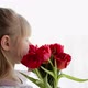 Smiling small girl holding and sniffing bouquet of red tulips. Greeting card - VideoHive Item for Sale