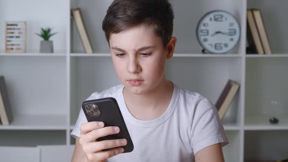 Portrait of a Boy of 13 Years Old Uses a Smartphone While Sitting at Home