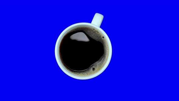 Small Coffee Cup with White Coffee on Saucer Rotating on Blue Screen, Loop, Top View. Alpha Channel.