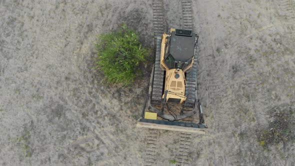 Top Aerial View on Tracked Bulldozer Rides on Sandy Road at Construction Site