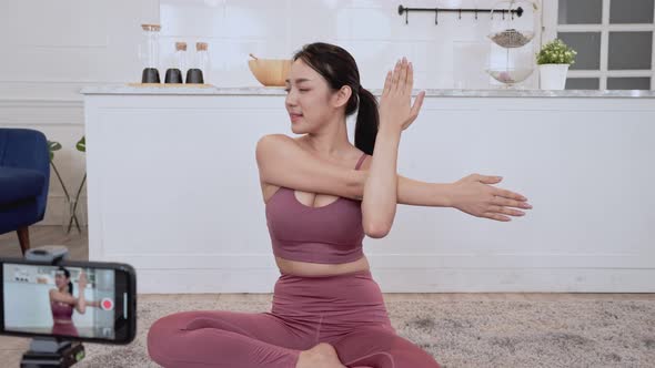 Asian woman in sportswear teaching yoga exercise on live streaming
