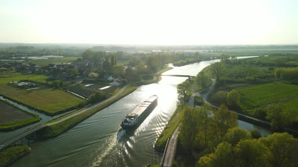 Aerial view in the sunset of a houseboat that goes under a bridge near Clairmarais, France. There ar