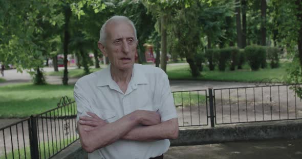 Portrait of Senior Man Crossing Hands and Looking Thoughtfully at Camera