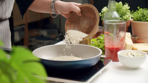 Cook pouring rice into pan while preparing dish