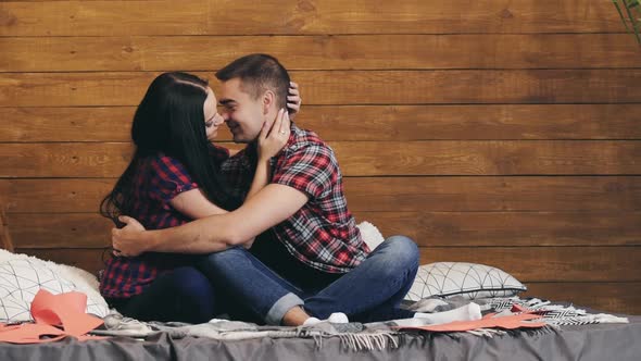 Happy Young Couple in Plaid Shirts are Hugging on the Bedroom 