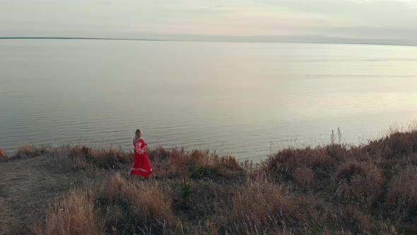 A Woman Warrior Standing on the Edge of Hill with a Sword and Wields It in Front of an Open River