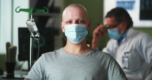 Bald Man in Mask Looking at Camera During Chemotherapy