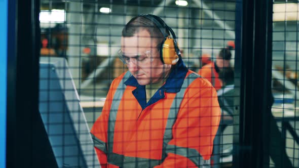 Factory Engineers in Safety Wear Filmed Through a Grid