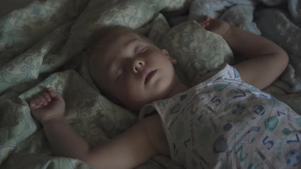 Peaceful carefree adorable baby boy sleeping on the bed in the room