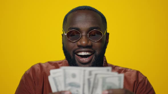 Portrait of Happy African American Man Counting Money on Yellow Background
