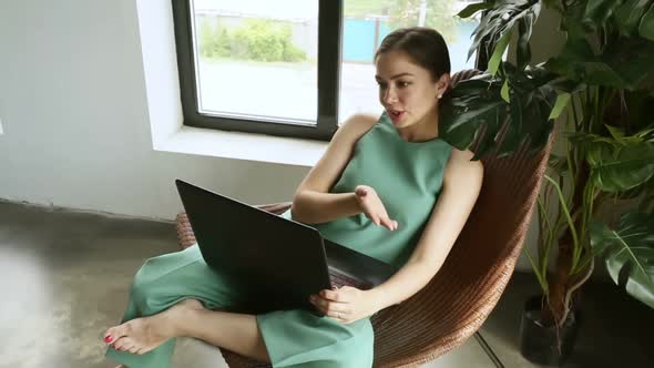 Young American Woman is Having Online Talk and Using Laptop at Home Room Iroi