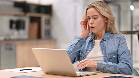 Young Woman with Headache Using Laptop at Work