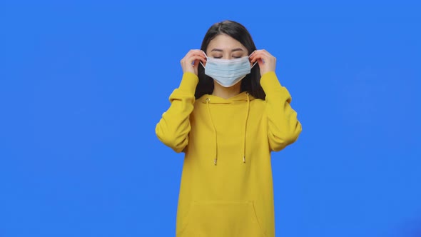 Portrait of Pretty Brunette Puts Medical Protective Mask