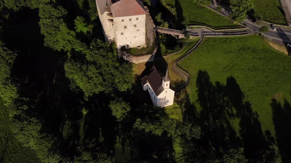 Top View Of The Lush Green Trees And The Small Church Beside Kaprun Castle In Salzburg, Austria. aer