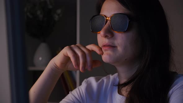 A Woman in Perforated Glasses Looks at the Computer Screen